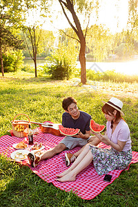 青年情侣坐在公园里吃西瓜图片素材