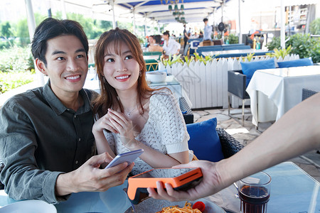 女朋友女人售货员年轻情侣在餐厅用手机付款欢乐高清图片素材