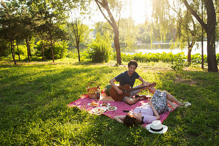 躺着约会的情侣东方人非都市风光日光在公园里弹吉他的幸福情侣背景