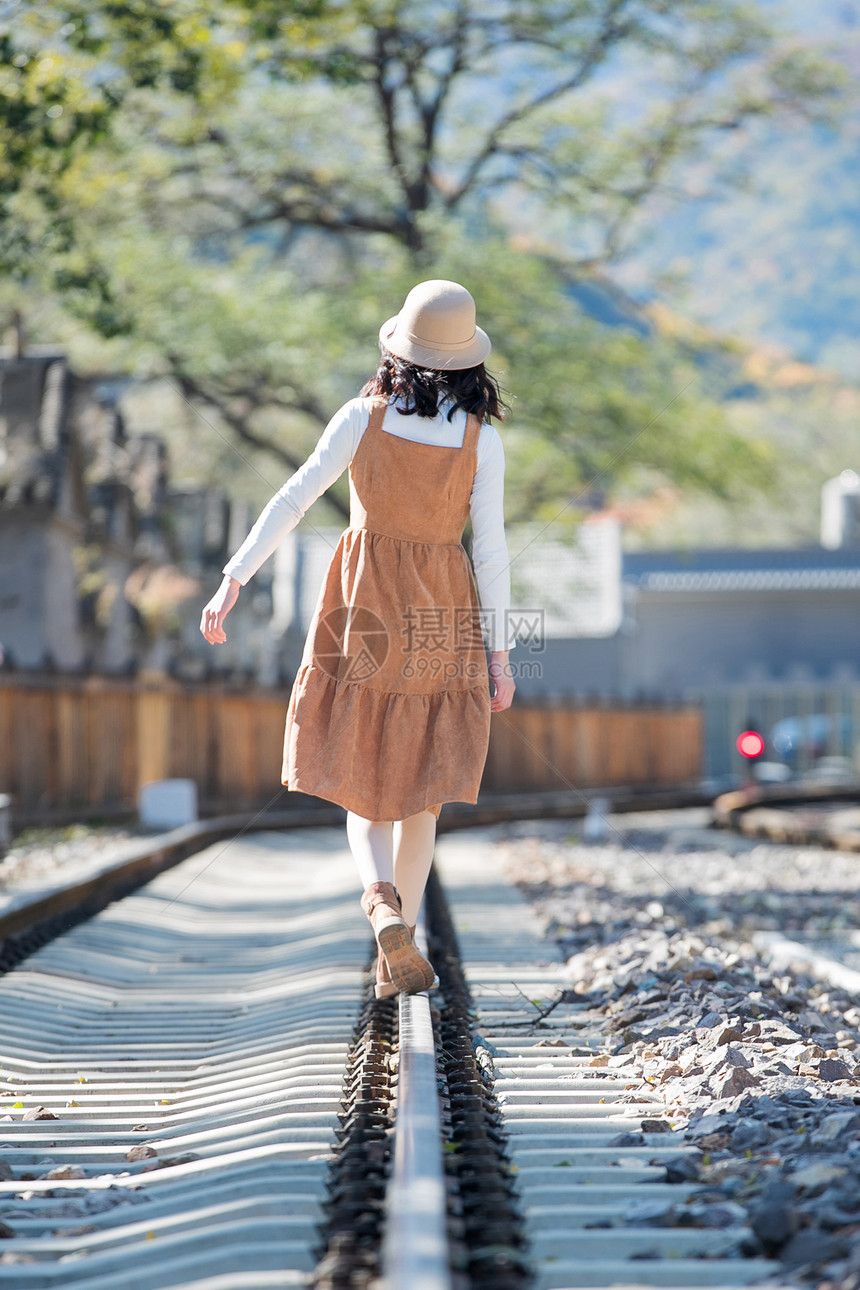 后背高雅美女青年女人在铁轨上行走图片