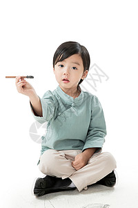 无忧无虑留白愉悦可爱的小男孩坐在地上用毛笔写字高清图片