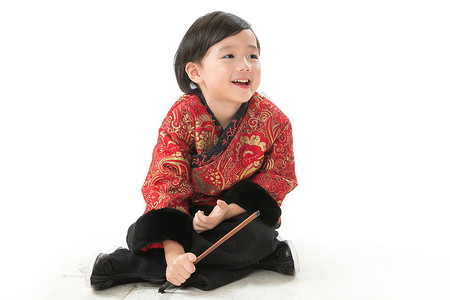 春节画画素材影棚拍摄传统庆典盘着腿坐可爱的小男孩坐在地上画画背景