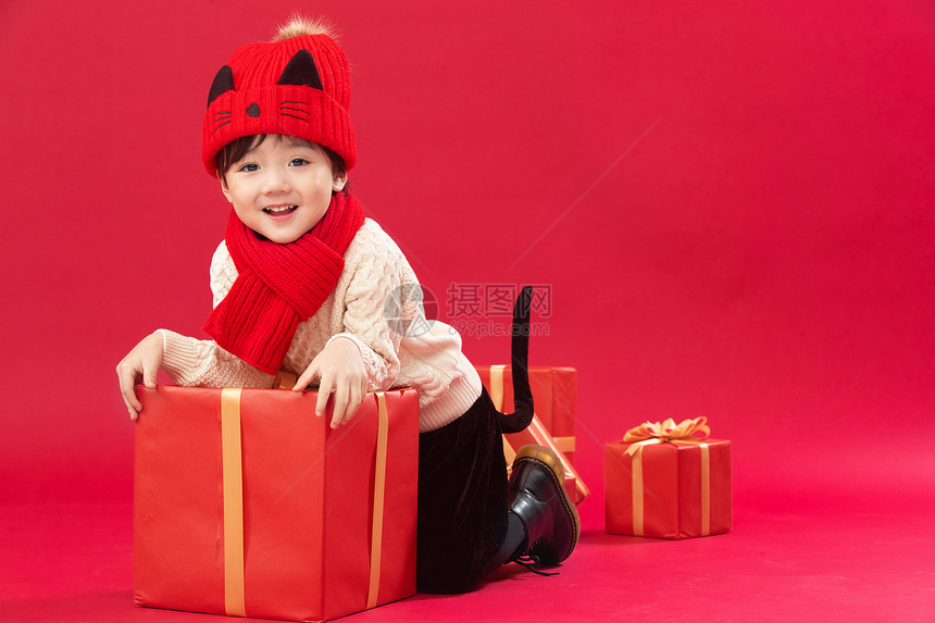 传统庆典包装盒祝福可爱的小男孩趴在新年礼物上玩耍图片