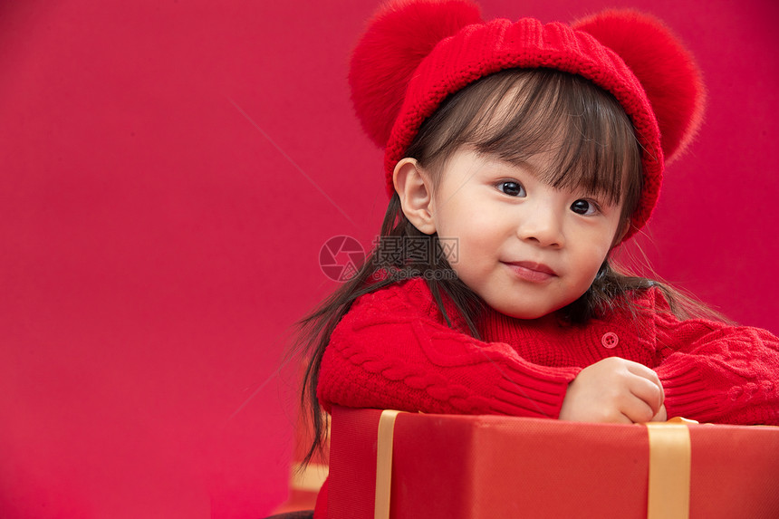 幸福祝福可爱的小女孩趴在新年礼物上图片