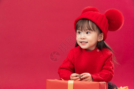 初心不改元素东方人不看镜头拜年可爱的小女孩趴在新年礼物上背景