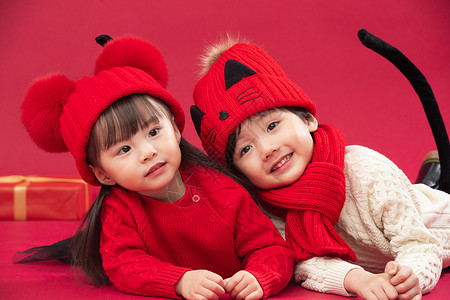 新年帽子儿童装扮传统庆典两个小朋友趴在地上玩耍背景