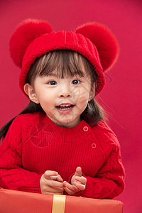 摄影注视镜头红色背景可爱的小女孩趴在新年礼物上图片