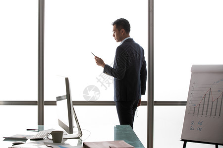 商务男士在窗户前看手机背景图片