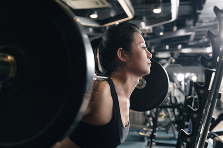 减肥运动年轻女子在健身房练习抗杠铃高清图片