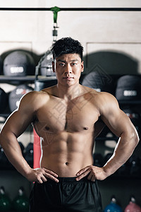 年轻男子在健身房展示肌肉背景图片