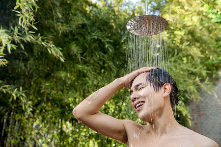 淋浴的人溅淋浴头彩色图片年轻男人在户外淋浴洗头背景
