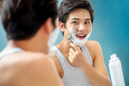 沐浴露泡沫个人护理泡沫青年男人对着镜子刮胡子背景