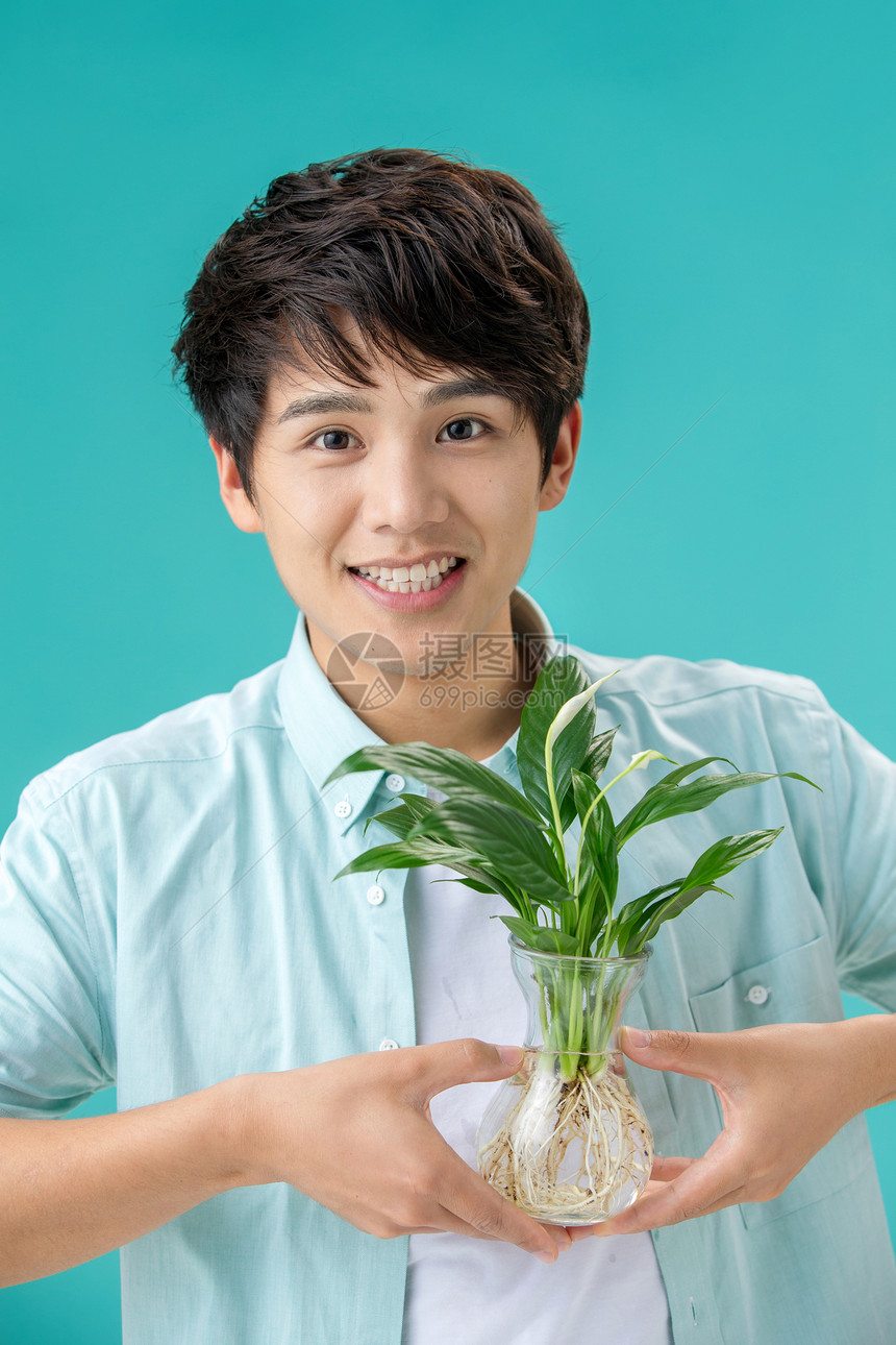 露齿一笑瓶子玻璃拿着绿色植物的青年男人图片