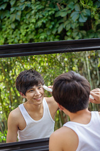 对着镜子洗脸的年轻男人高清图片