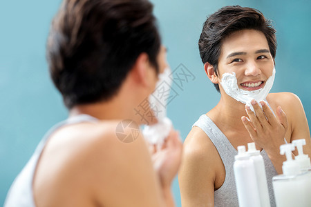 沐浴露泡沫青年男人对着镜子涂抹剃须膏背景