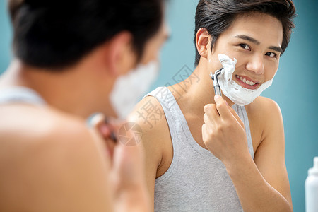 沐浴露泡沫青年男人对着镜子刮胡子背景