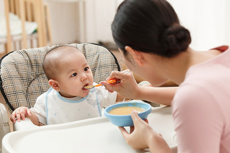 用勺子盛粥人妈妈喂宝宝吃饭背景