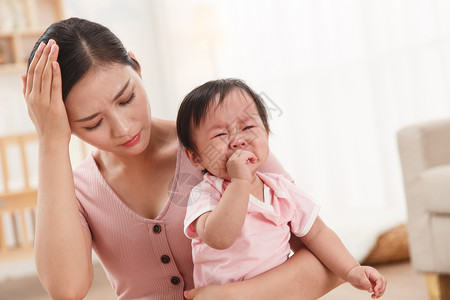 小孩惹妈妈生气头疼的妈妈和哭泣的宝宝背景