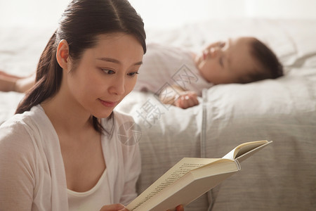 卧室年轻妈妈看书躺着高清图片素材
