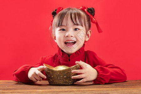 庆祝儿童节快乐纯洁发髻可爱的小女孩拿着金元宝过新年背景