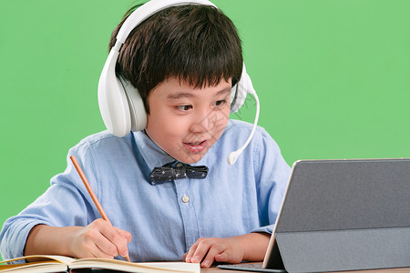 铅笔绿色背景东方人小学生使用平板电脑在线学习可爱的高清图片素材