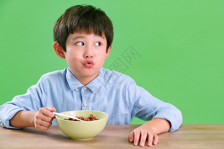 吃饭咯表情绿色背景有趣的快乐小男孩吃东西背景
