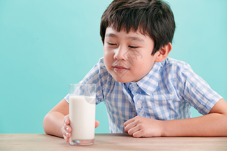 磨豆浆的孩子快乐可爱的清新小男孩看着一杯牛奶背景