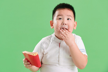 影棚拍摄童年关爱可爱的小男孩吃薯条背景
