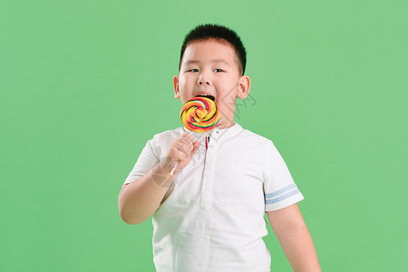 好好吃表情清新不健康食物微笑可爱的小男孩拿着棒棒糖背景