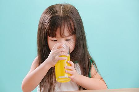摄影肖像好奇心可爱的小女孩喝饮料蓝色背景高清图片素材