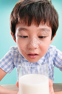 关爱可爱的8岁到9岁小男孩看着一杯牛奶饮料高清图片素材