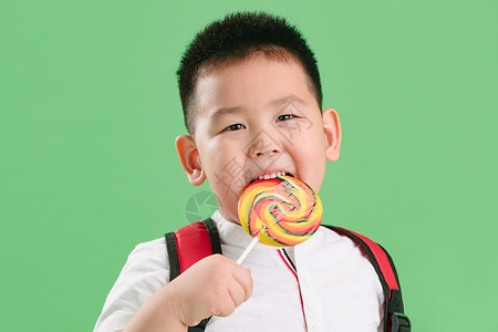 吃完了表情无忧无虑亚洲可爱的小男孩拿着棒棒糖背景