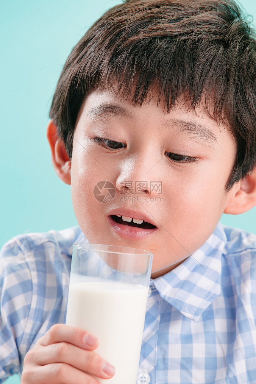 无忧无虑学龄儿童可爱的小男孩看着一杯牛奶图片