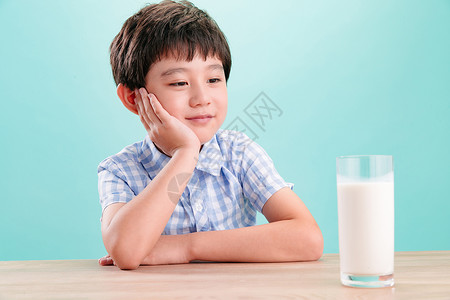 清新关爱小男孩看着一杯牛奶希望高清图片素材