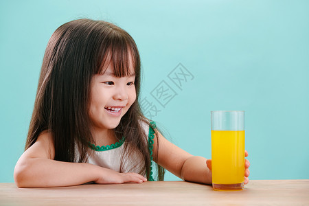 长发微笑学龄前儿童可爱的小女孩喝饮料图片