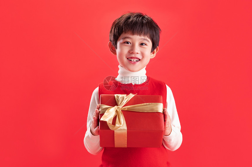 天真红色背景礼品小男孩拿新年礼物图片