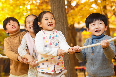 秋天树林中小学生在拔河比赛背景图片