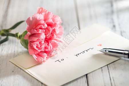 萱草母亲花桌上的康乃馨花和信封贺卡背景
