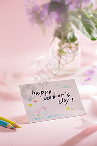 粉紫色妈妈贺卡桌上的康乃馨花和信封贺卡背景