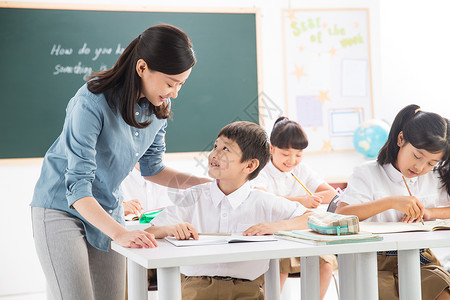 在写字的学生老师和小学生们在教室里背景