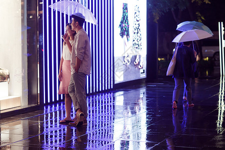 打伞约会的情侣下雨天夜里一起逛街的情侣背景