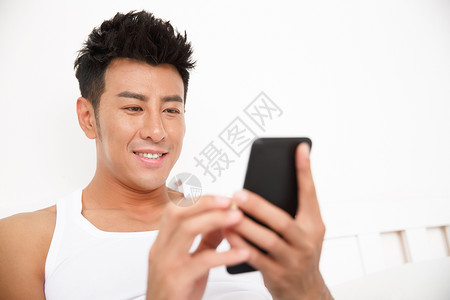 幸福舒适网上冲浪青年男人在卧室玩手机图片素材