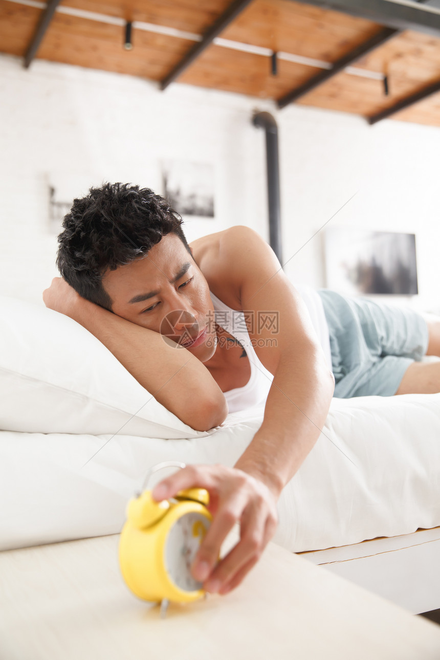 室内闹钟背心青年男人在卧室睡觉图片