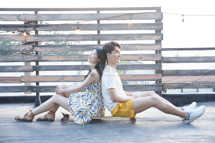 摄影亚洲人休闲活动青年情侣坐在滑板上图片