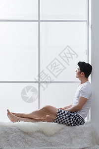 全身像时尚起居室青年男人坐在窗户旁边生活方式高清图片素材