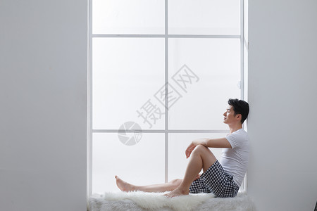 25岁到29岁客厅起居室青年男人坐在窗户旁边白昼高清图片素材