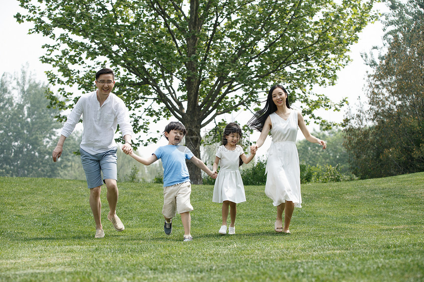 休闲休闲装快乐家庭在草地上奔跑图片