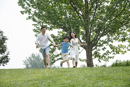 家庭三个人一家三口在草地上奔跑图片