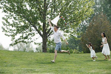 5到6岁健康生活方式女孩一家三口在草地上放风筝高清图片