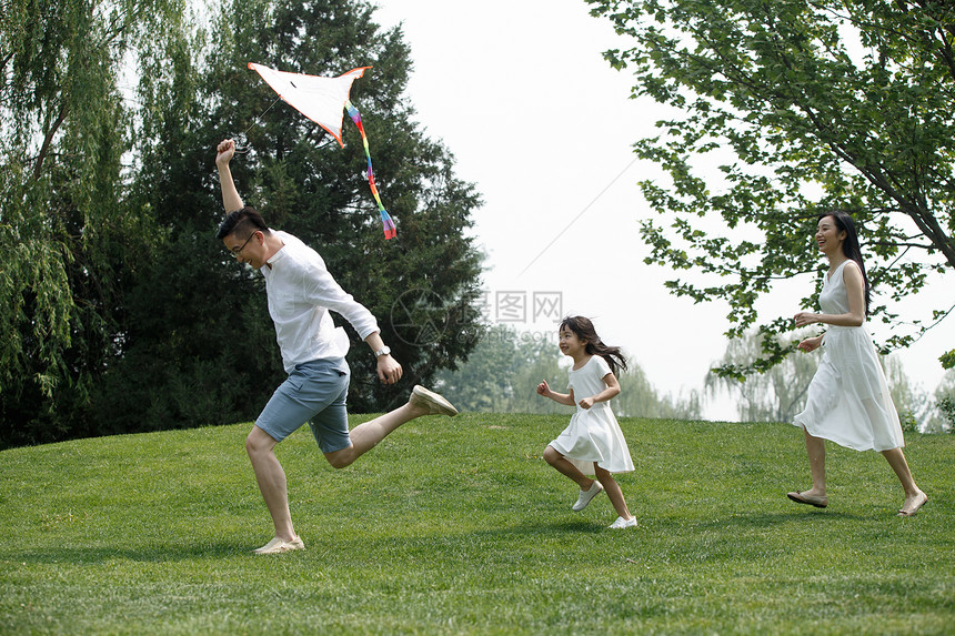 双亲家庭25岁到29岁爱一家三口在草地上放风筝图片